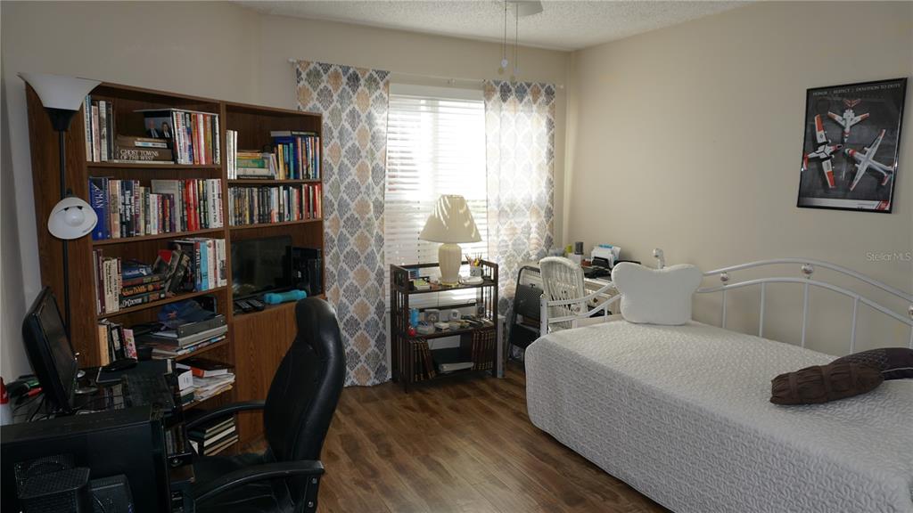 11241 Versailles Lane Port Richey, FL 34668 - Photo 18 of 38 a bedroom with a bed a table and a large window