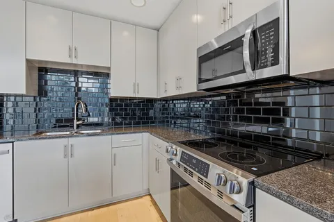 a kitchen with granite countertop a stove sink and cabinets