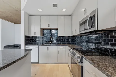 a kitchen with granite countertop a sink a stove and cabinets