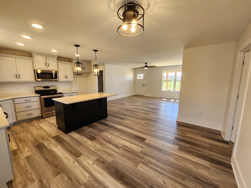 670 Armstrong Road Castalian Springs, TN 37031 - Photo 7 of 25 a large kitchen with stainless steel appliances granite countertop a sink dishwasher a stove and a dining table with wooden floor