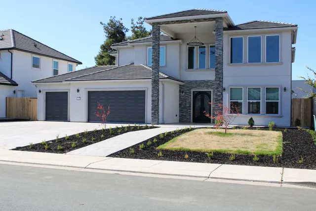 a front view of a house with garden and garage
