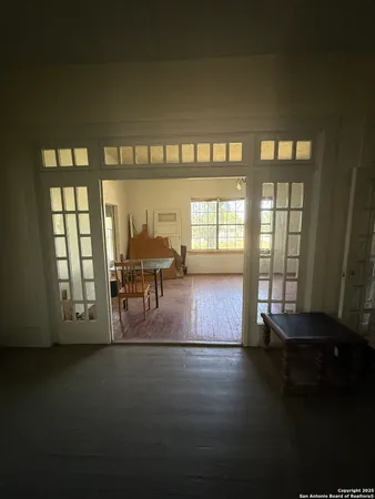 a view of an empty room with window and chandelier fan