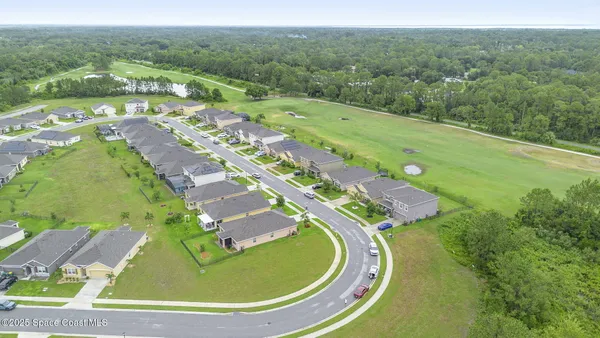 a aerial view of a house with table and chairs next to a yard