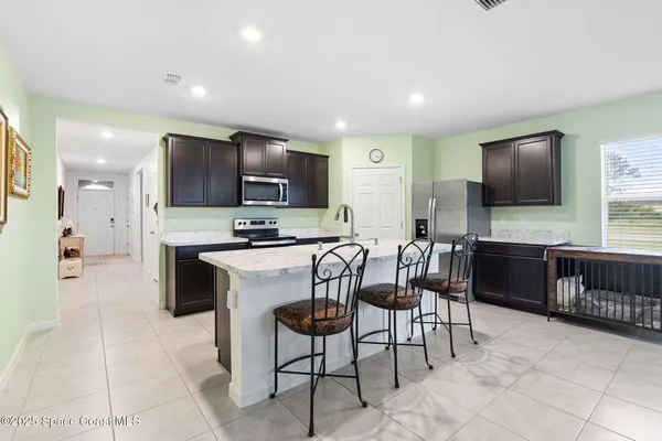 a kitchen with stainless steel appliances kitchen island granite countertop a stove a sink a microwave a dining table and chairs