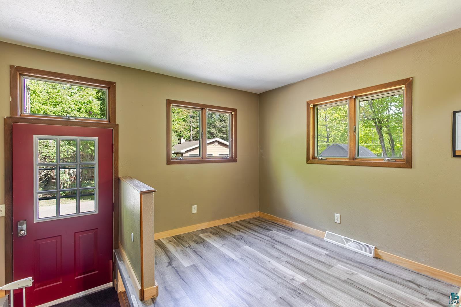 7045 Morris Thomas Road Cloquet, MN 55720 - Photo 5 of 28 Entryway featuring a deep red door with grid-pane window, transom window, and Dining room with wood-finish flooring