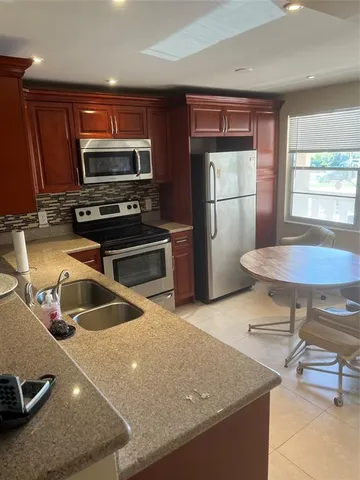 a kitchen with stainless steel appliances granite countertop a sink a stove and a refrigerator