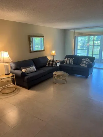 a living room with couches and a large window with rug floor