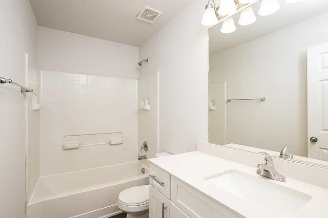 a bathroom with a sink a toilet a mirror and shower