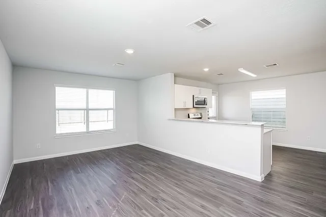 a living room with stainless steel appliances kitchen island wooden floor and window