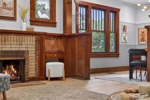a living room with a fireplace furniture a ceiling fan and a window