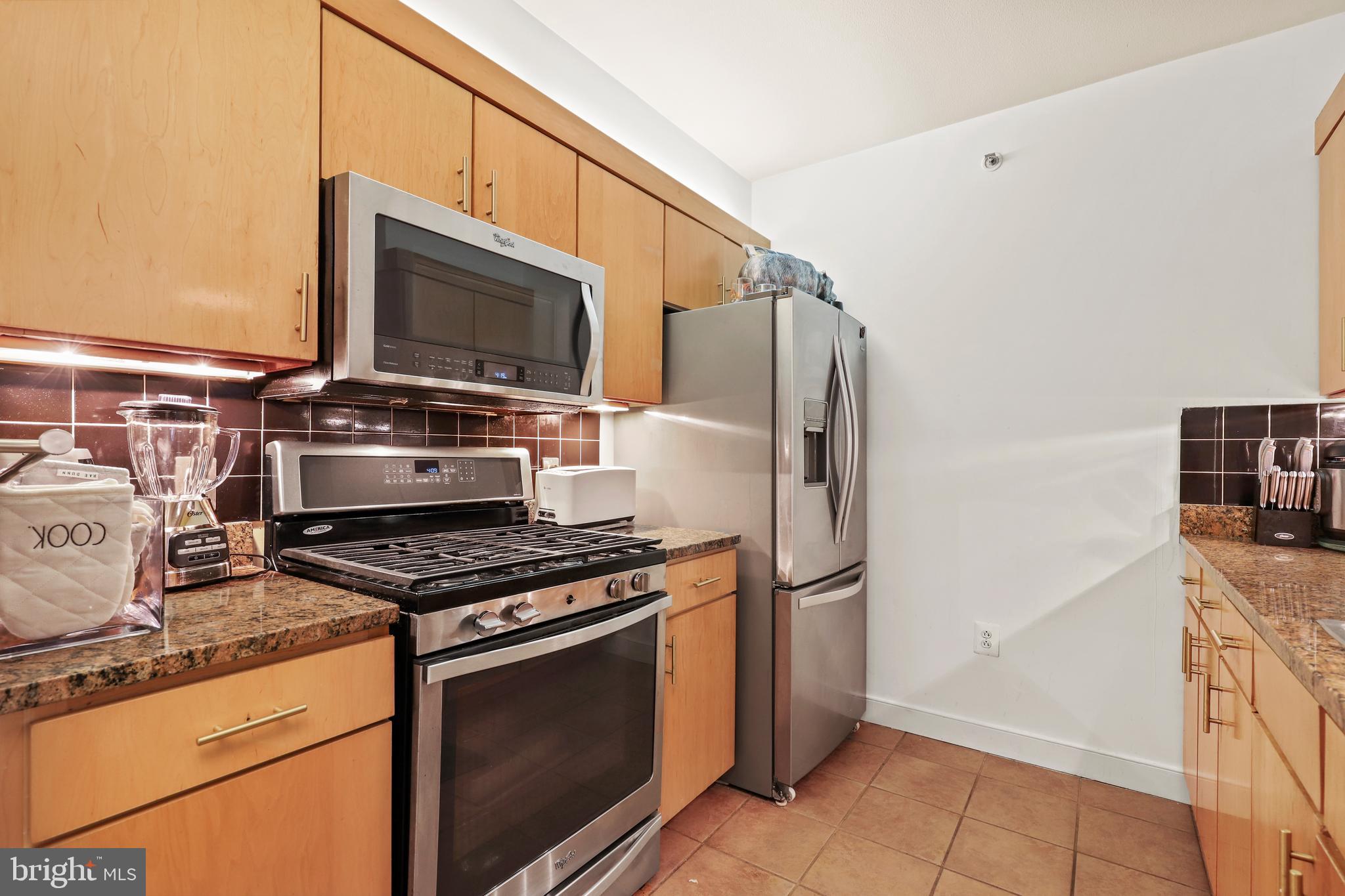 616 E Street Northwest, Unit 1007 Washington, DC 20004 - Photo 26 of 99 a kitchen with stainless steel appliances granite countertop a stove and a refrigerator