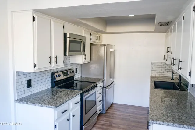 a kitchen with stainless steel appliances granite countertop a sink and a refrigerator