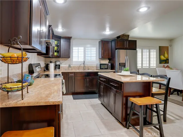 a kitchen with stainless steel appliances granite countertop wooden cabinets a sink a stove a dining table and chairs