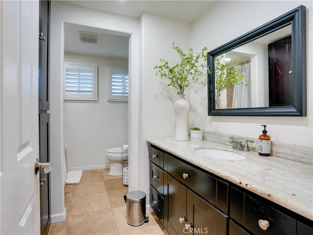 a bathroom with a granite countertop sink and a toilet