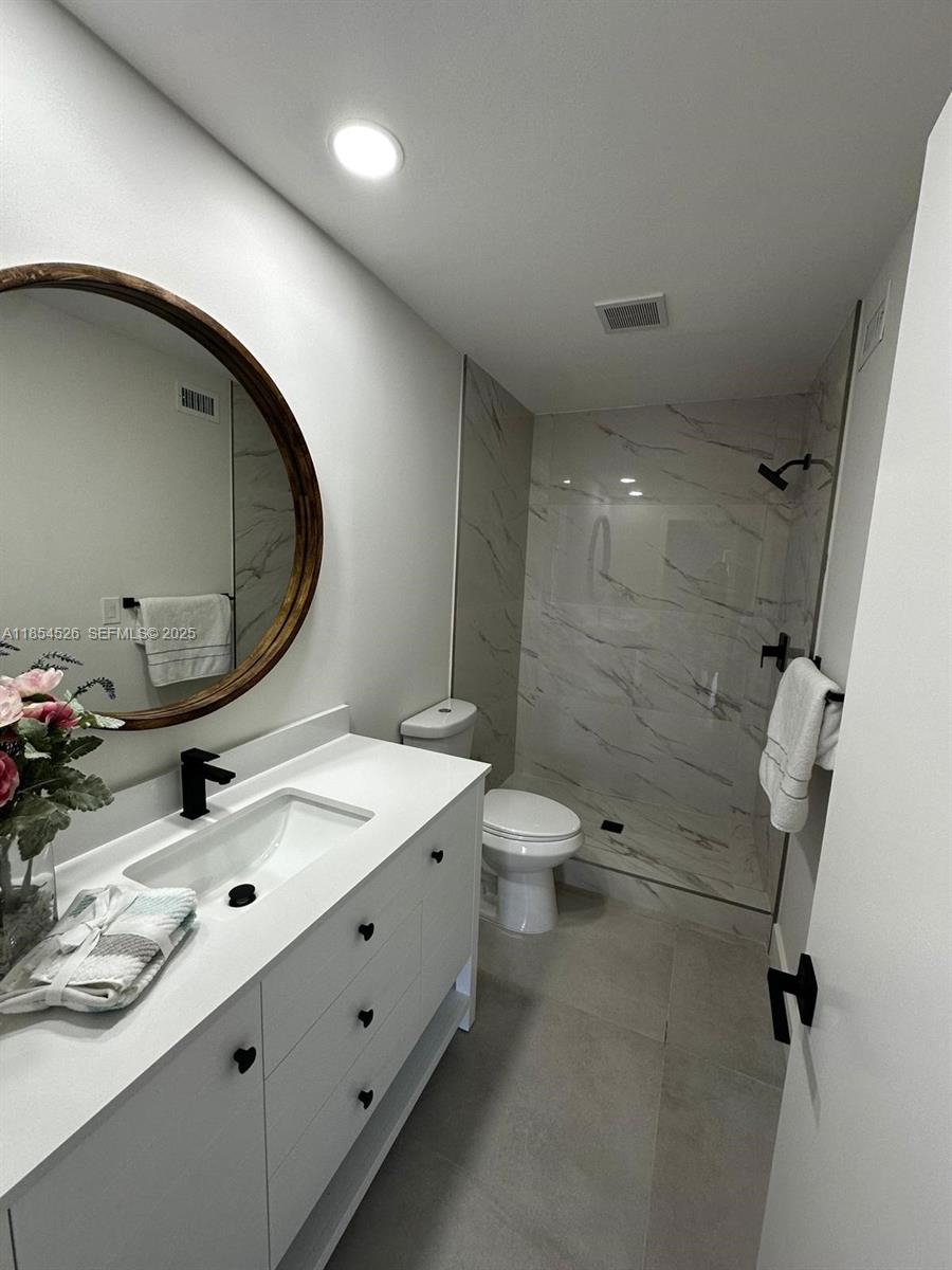 316 Cape Cod Circle, Unit B Lake Worth, FL 33467 - Photo 17 of 38 a bathroom with a double vanity sink toilet mirror and shower