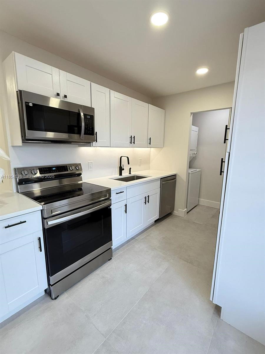 316 Cape Cod Circle, Unit B Lake Worth, FL 33467 - Photo 2 of 38 a kitchen with stainless steel appliances a stove a microwave and white cabinets
