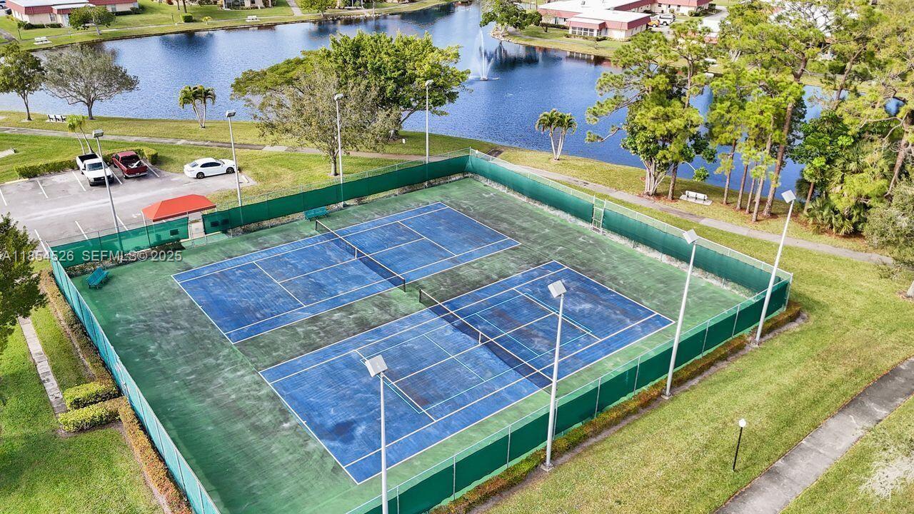 316 Cape Cod Circle, Unit B Lake Worth, FL 33467 - Photo 30 of 38 a view of a tennis ground with large trees