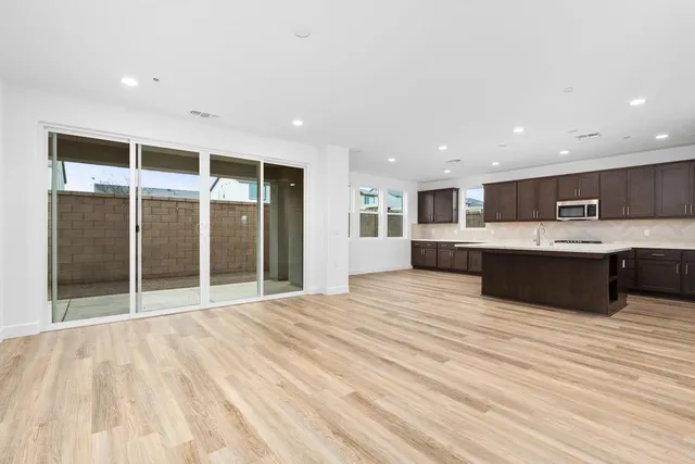 a large white kitchen with kitchen island a sink stainless steel appliances and cabinets