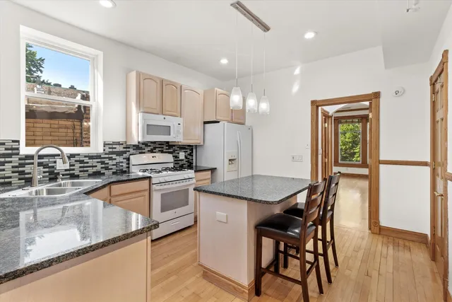 a kitchen with stainless steel appliances granite countertop table chairs sink and cabinets