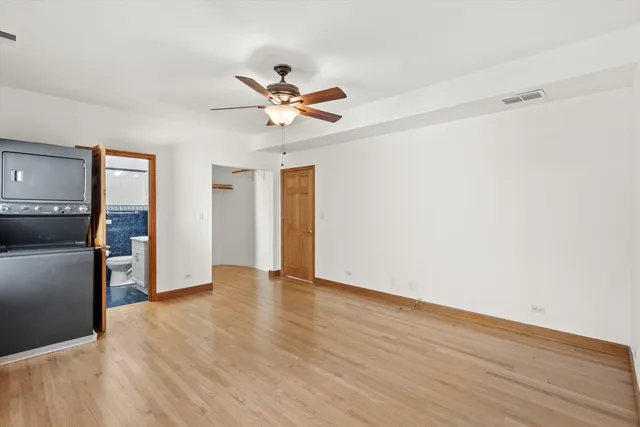 an empty room with wooden floor closet and windows