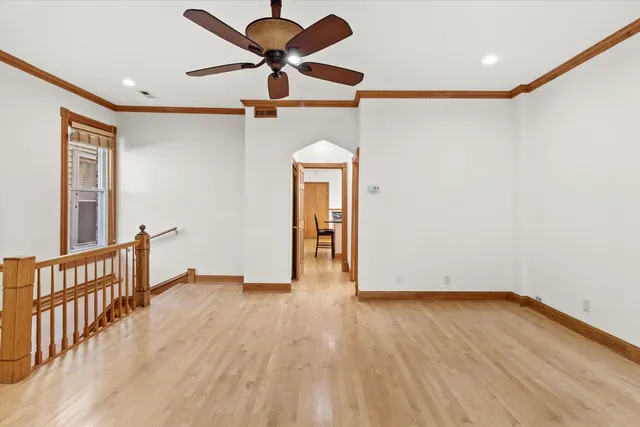 a view of empty room with wooden floor and fan