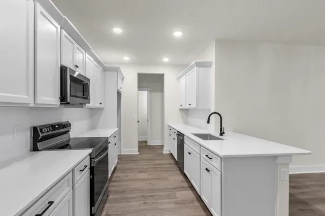 a large white kitchen with stainless steel appliances granite countertop lots of counter top space and cabinets