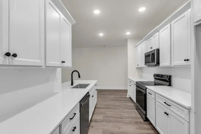 a kitchen with granite countertop a sink dishwasher stove and microwave with wooden floor