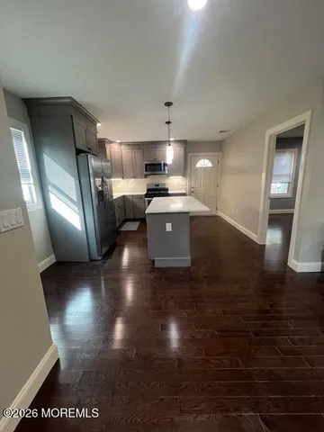 a view of kitchen with stainless steel appliances granite countertop a refrigerator a sink dishwasher and wooden floor