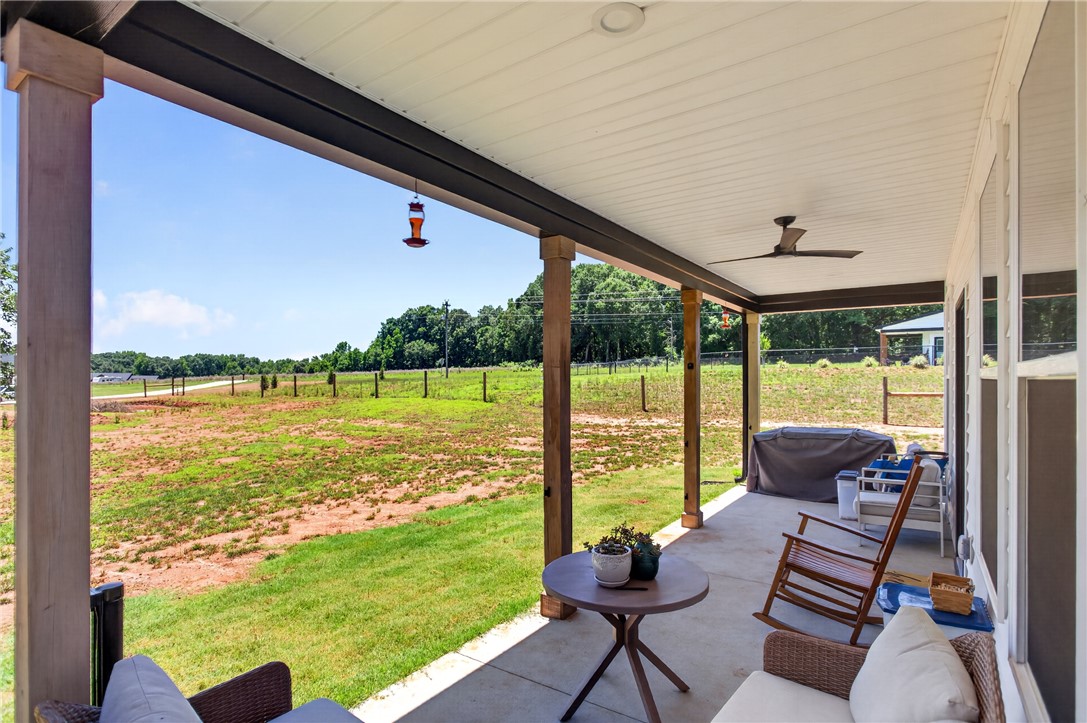 106 Bolt Road Townville, SC 29689 - Photo 30 of 33 A spacious covered patio invites relaxation with panoramic views of the verdant yard and distant tree line.