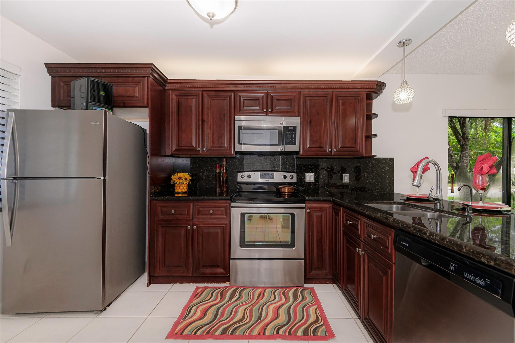 340 Racquet Club Road, Unit 101 Weston, FL 33326 - Photo 12 of 29 a kitchen with stainless steel appliances granite countertop a refrigerator and a stove top oven