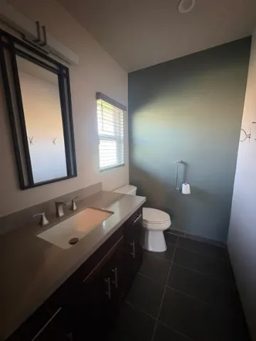 a bathroom with a granite countertop sink toilet and mirror