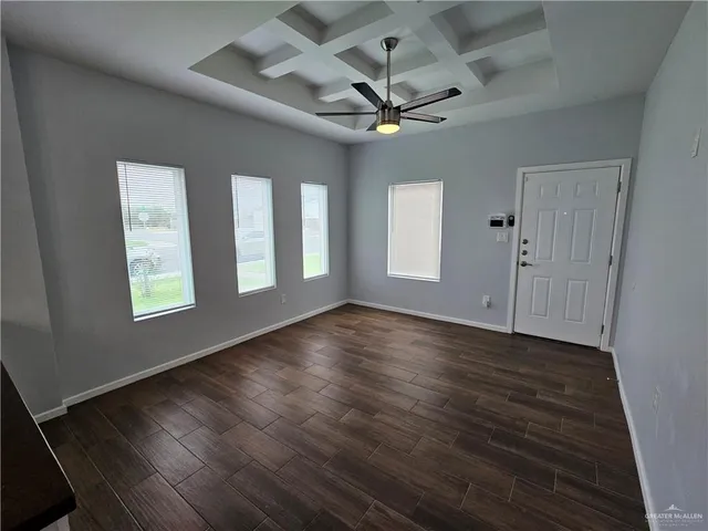 an empty room with wooden floor fan and windows