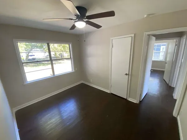 a view of an empty room with wooden floor and a window