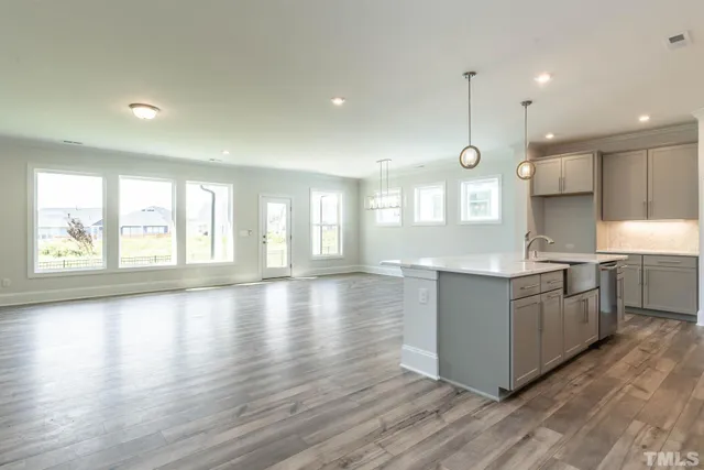 a large kitchen with stainless steel appliances granite countertop a stove a sink a refrigerator and white cabinets with wooden floor