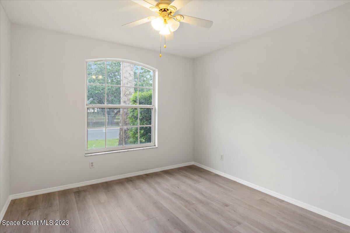 2405 Ruffner Road Melbourne, FL 32901 - Photo 23 of 35 an empty room with wooden floor fan and windows
