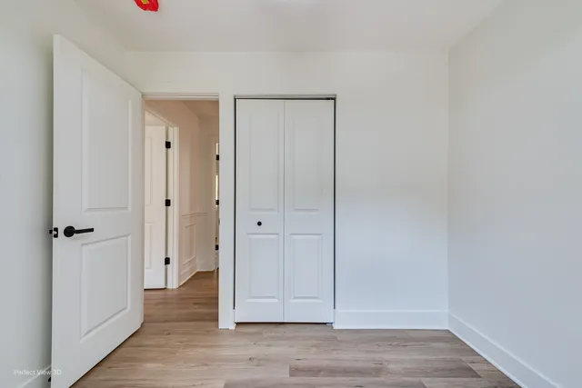 an empty room with wooden floor staircase and windows