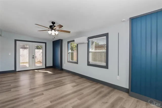 a view of an empty room with a window and wooden floor