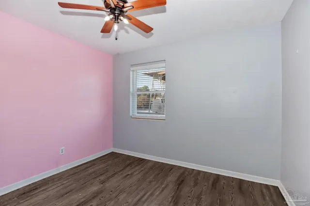 a view of an empty room with window and a chandelier fan