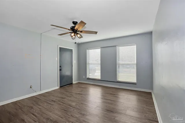 a view of an empty room with a window and wooden floor