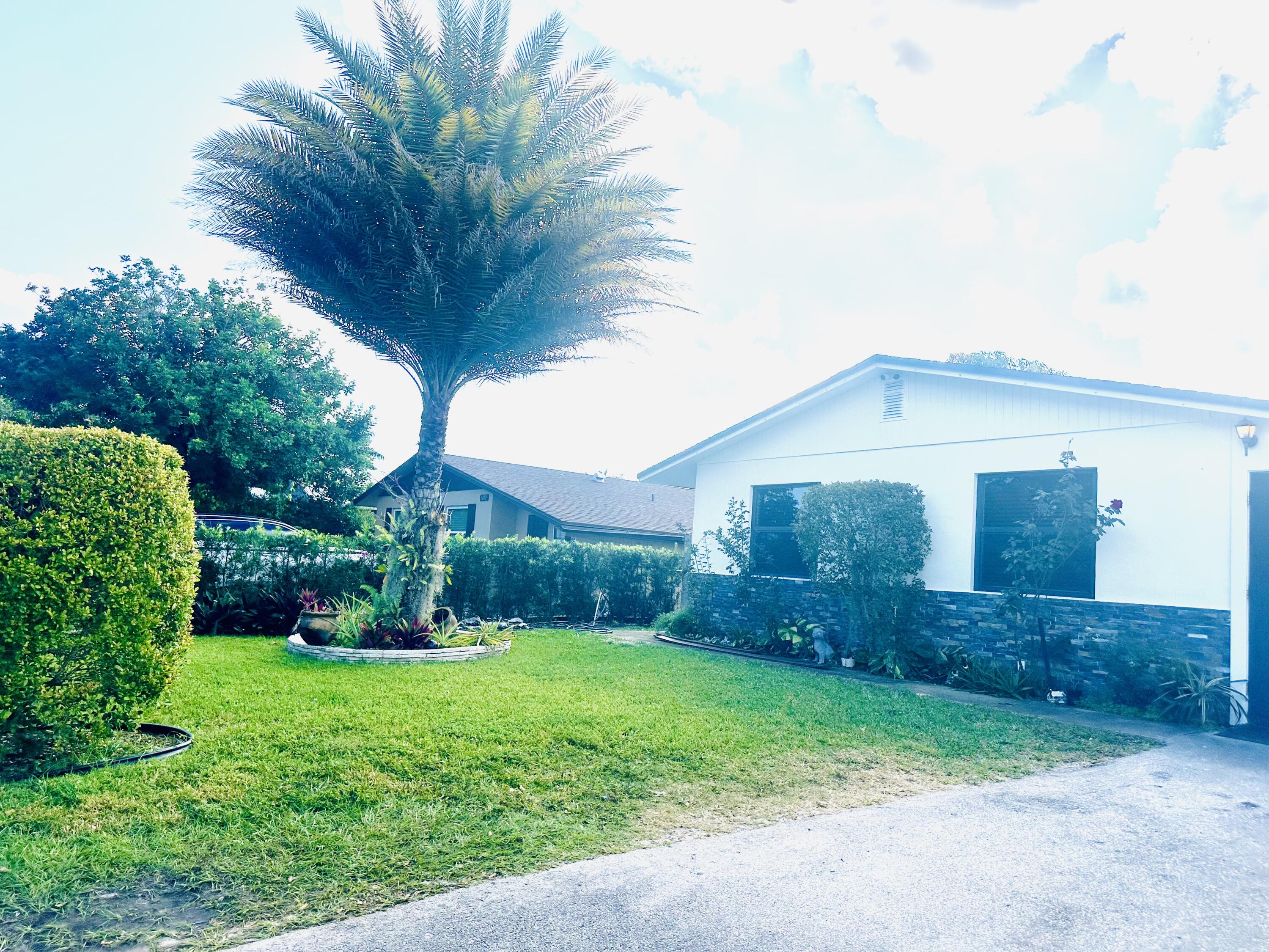 1104 Neoga Street Jupiter, FL 33458 - Photo 2 of 21 a view of a backyard with potted plants and large tree
