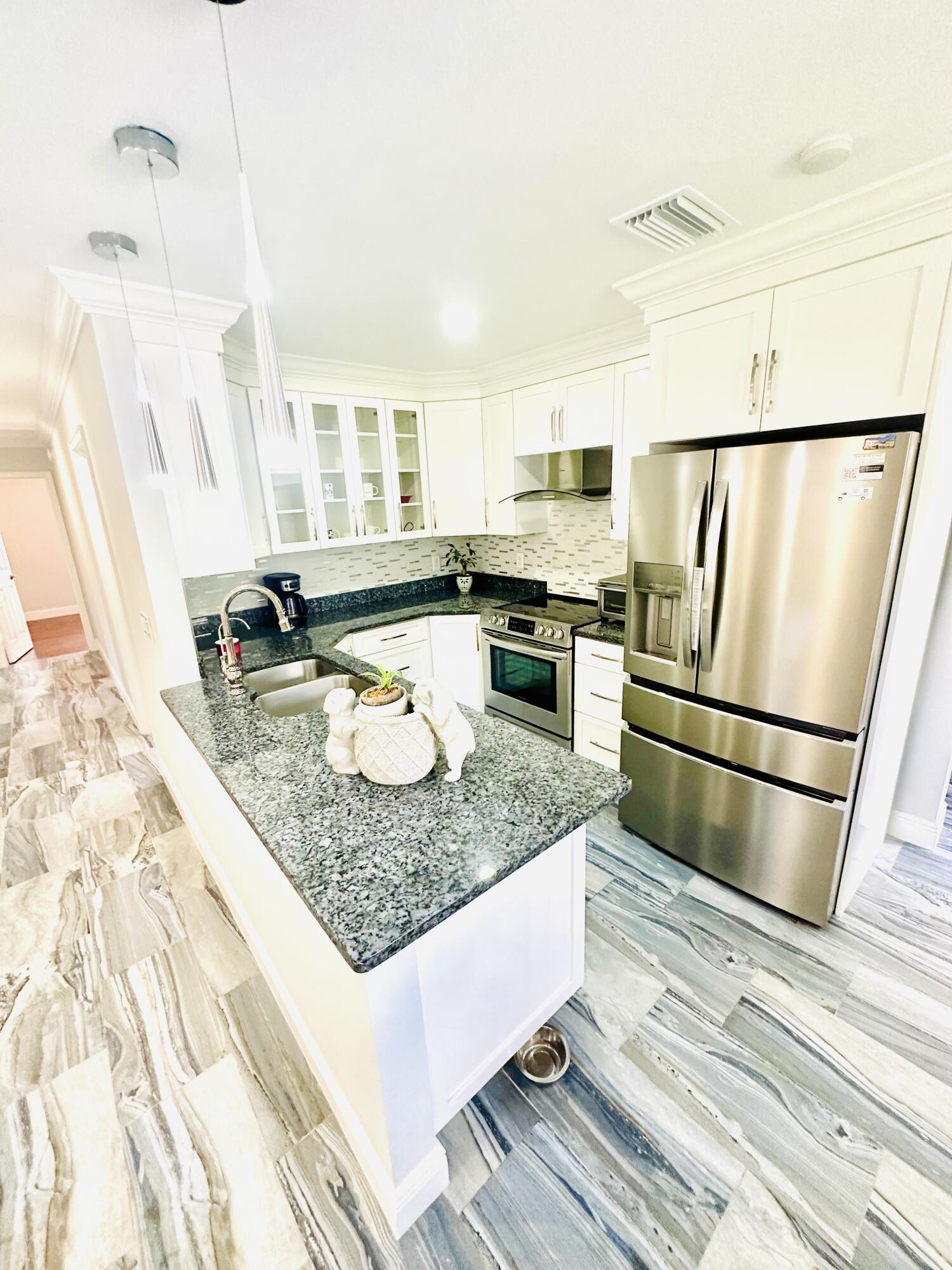 1104 Neoga Street Jupiter, FL 33458 - Photo 10 of 21 a kitchen with stainless steel appliances granite countertop a sink stove and refrigerator