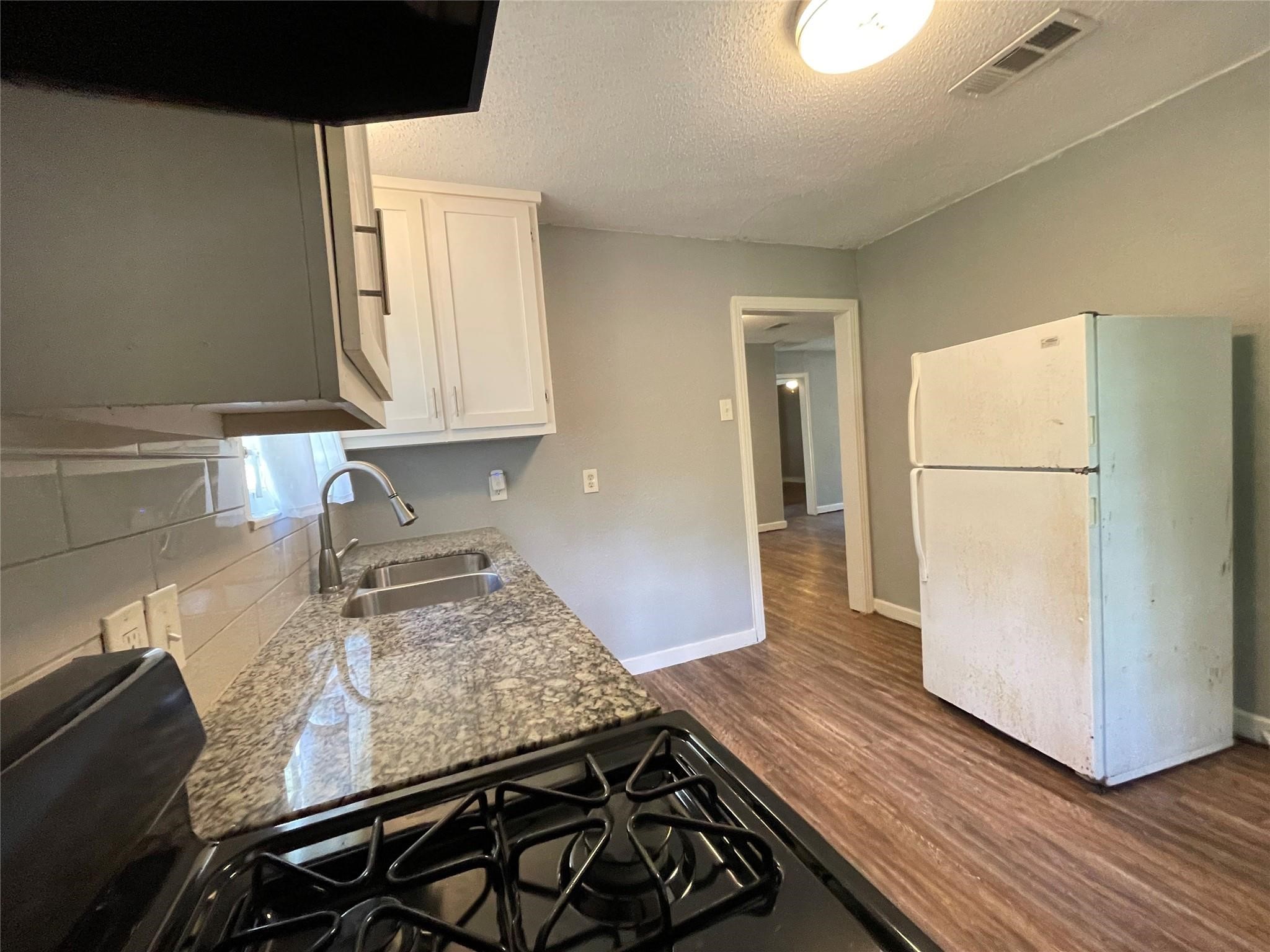 5213 Anzio Road Houston, TX 77033 - Photo 8 of 20 a kitchen with a wooden floor and a stove top oven