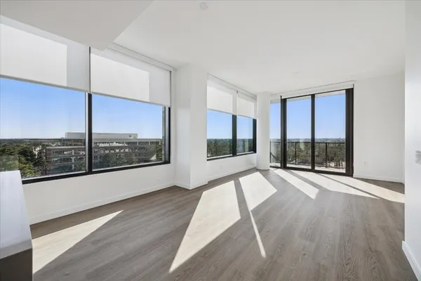 a view of an empty room with a window and wooden floor