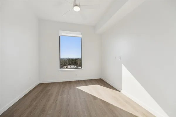 a view of an empty room with wooden floor and a window