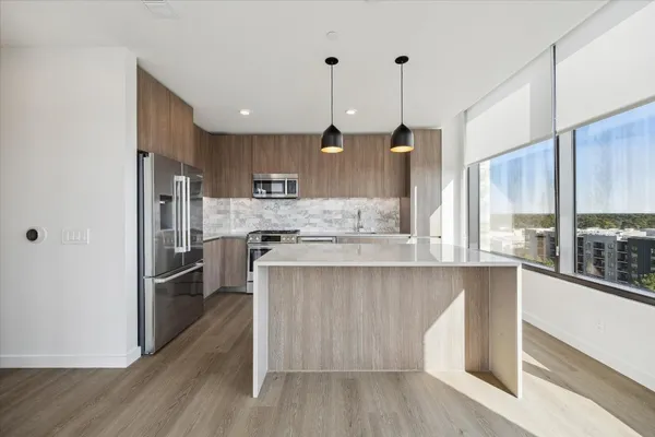 a kitchen with stainless steel appliances granite countertop a refrigerator a sink a stove and white cabinets with wooden floor