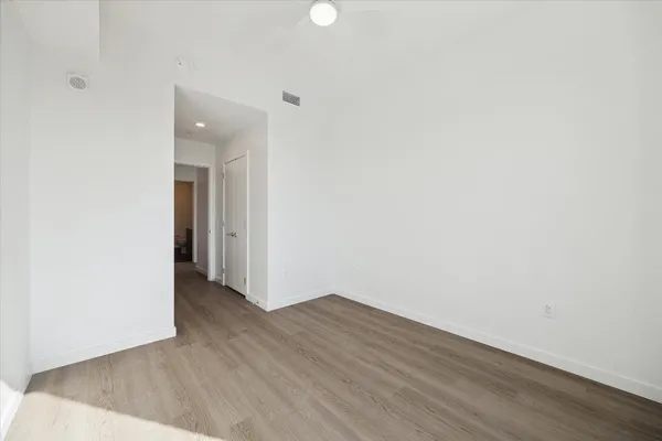 a view of an empty room with wooden floor and a bathroom