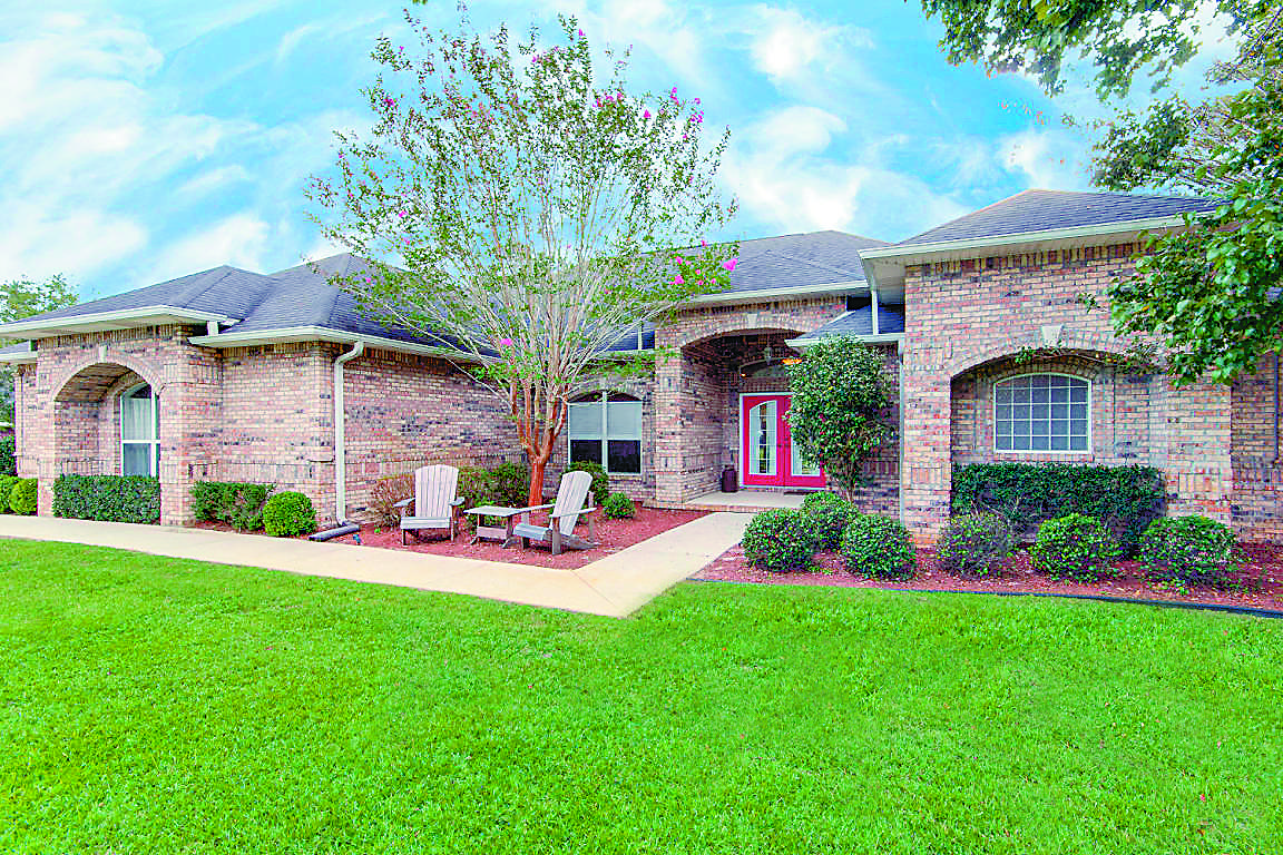2573 Cove Road Navarre, FL 32566 - Photo 1 of 28 a front view of a house with a garden and plants