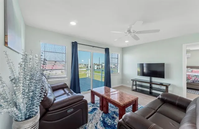 a living room with furniture a ceiling fan and a flat screen tv
