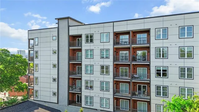 a front view of a building with glass windows and plants