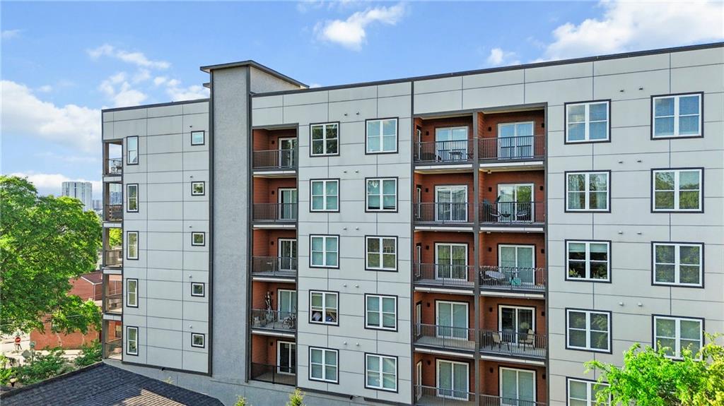 a front view of a building with glass windows and plants